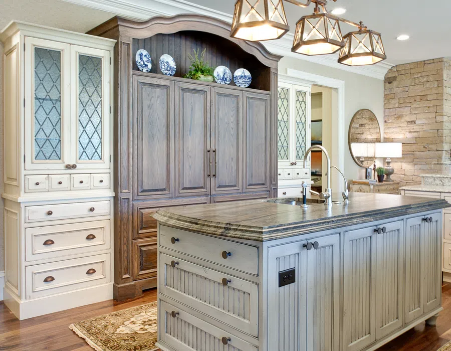 Elegant kitchen with a large wooden island, ornate ceiling light fixture, and hardwood floors with decorative rugs.