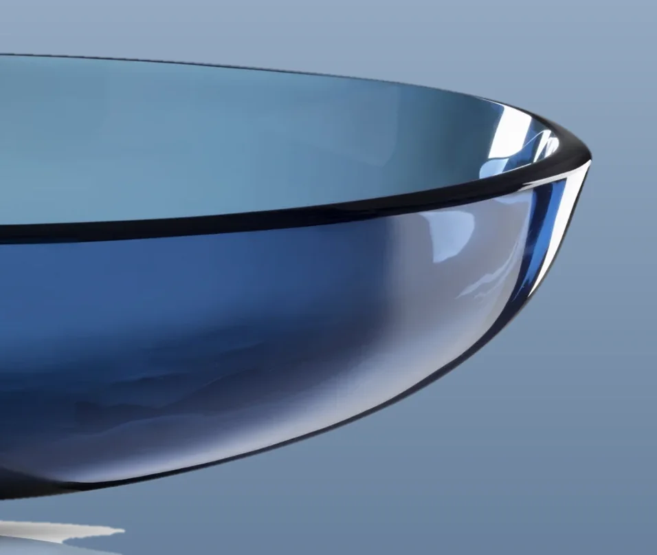 Edge of a translucent cobalt-blue glass vessel sink against a slate-blue backdrop